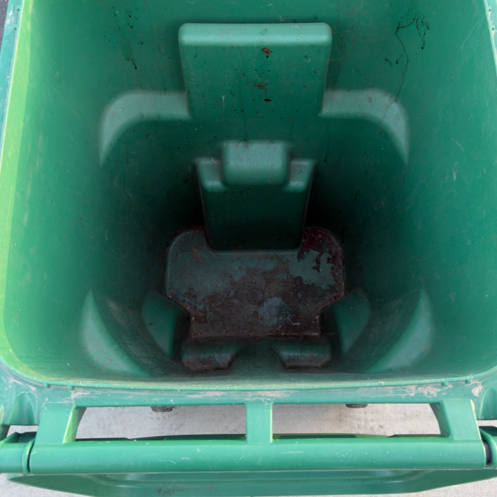 A stained green compost bin interior before cleaning