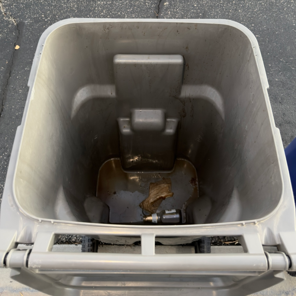 A stained gray trash bin interior before cleaning